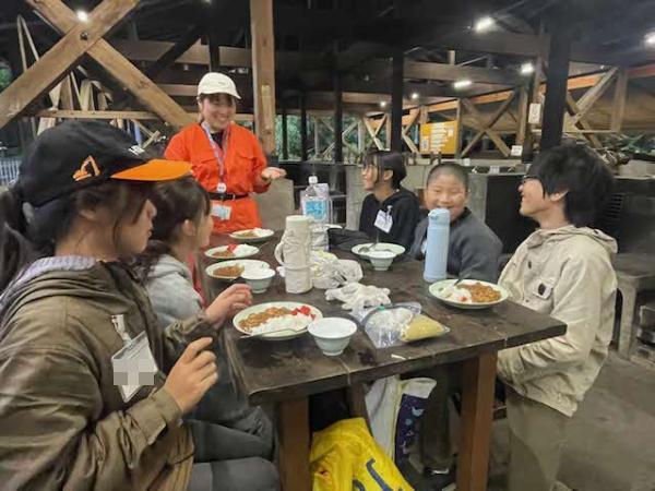 野外炊事でカレーを食べる様子