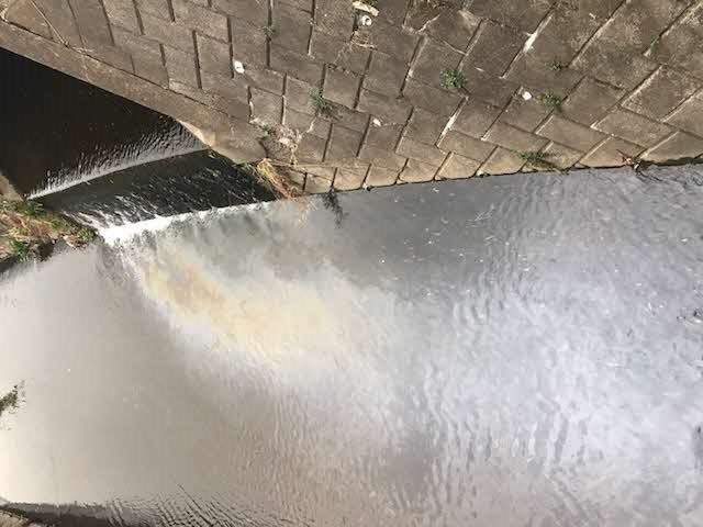 油が流出され色が変わっている河川の写真
