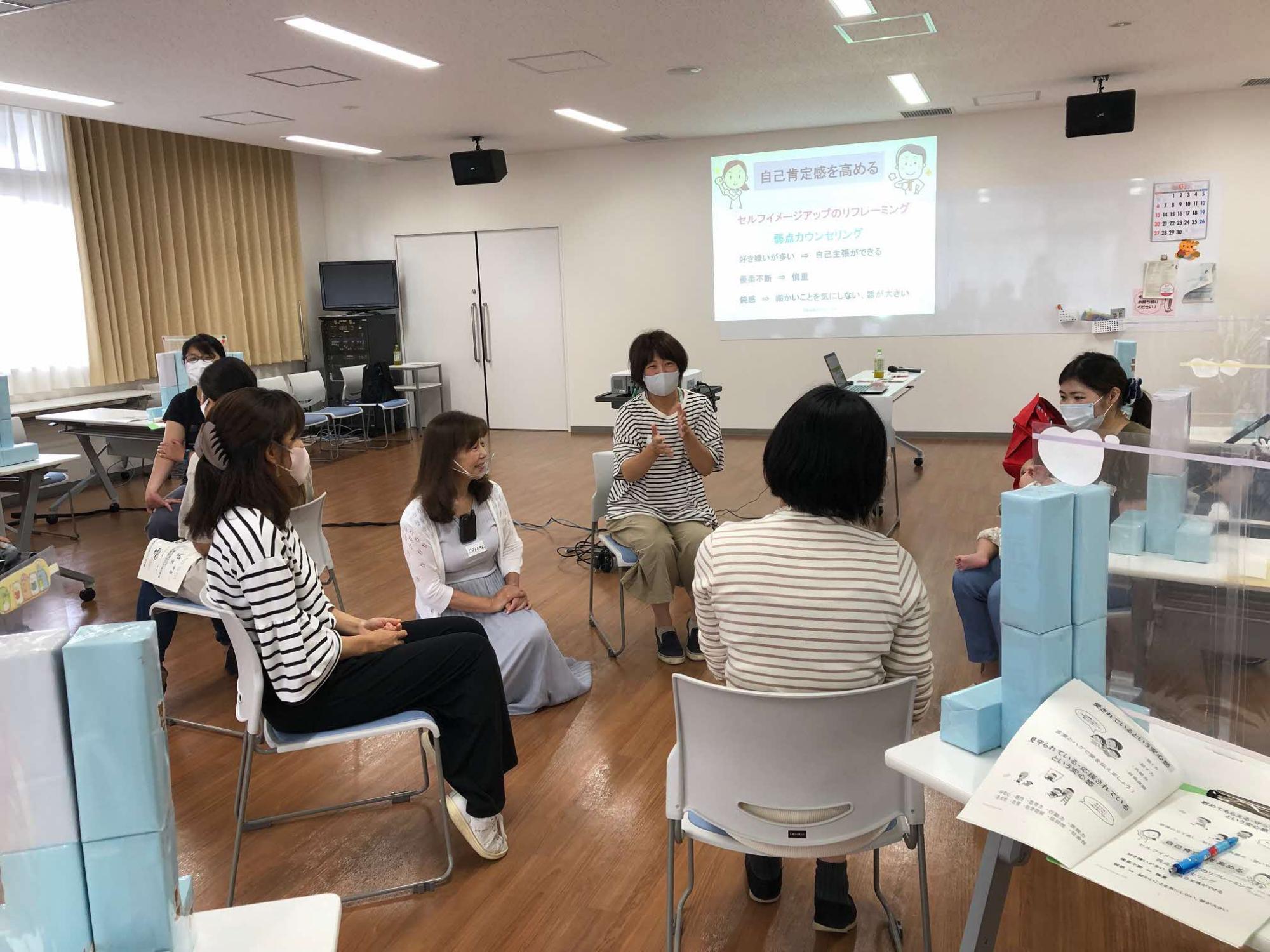 グループごとに分かれて丸い円を作って椅子に座り、グループの参加者同士で話をしているグループワークの様子の写真