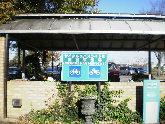屋根付きの駐輪場の前に建てられた「サイクル&バスライド用自転車置場」と書かれ自転車とバイクの絵が描かれた看板の写真