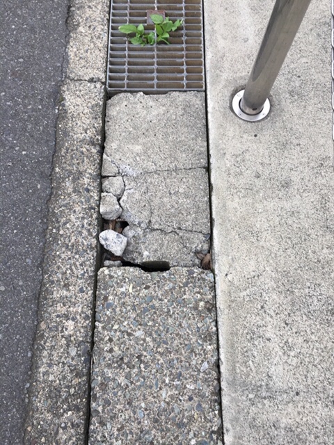 側溝にひび割れがある道路の写真