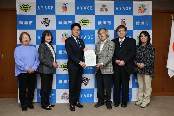 橘川市長に報告書を提出する様子 （左から小林委員、手塚副委員長、橘川市長、剱持委員長、永田委員、大部委員）