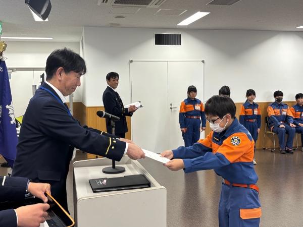 令和8年度少年消防クラブのリーダーが、任命証を授与しているところ