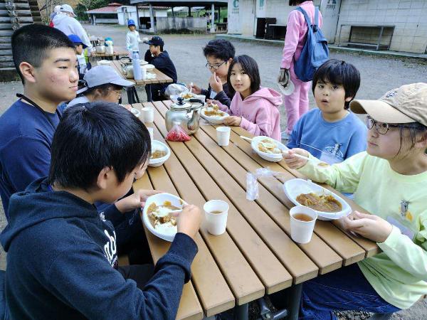 野外炊事でカレーライスを食べる様子