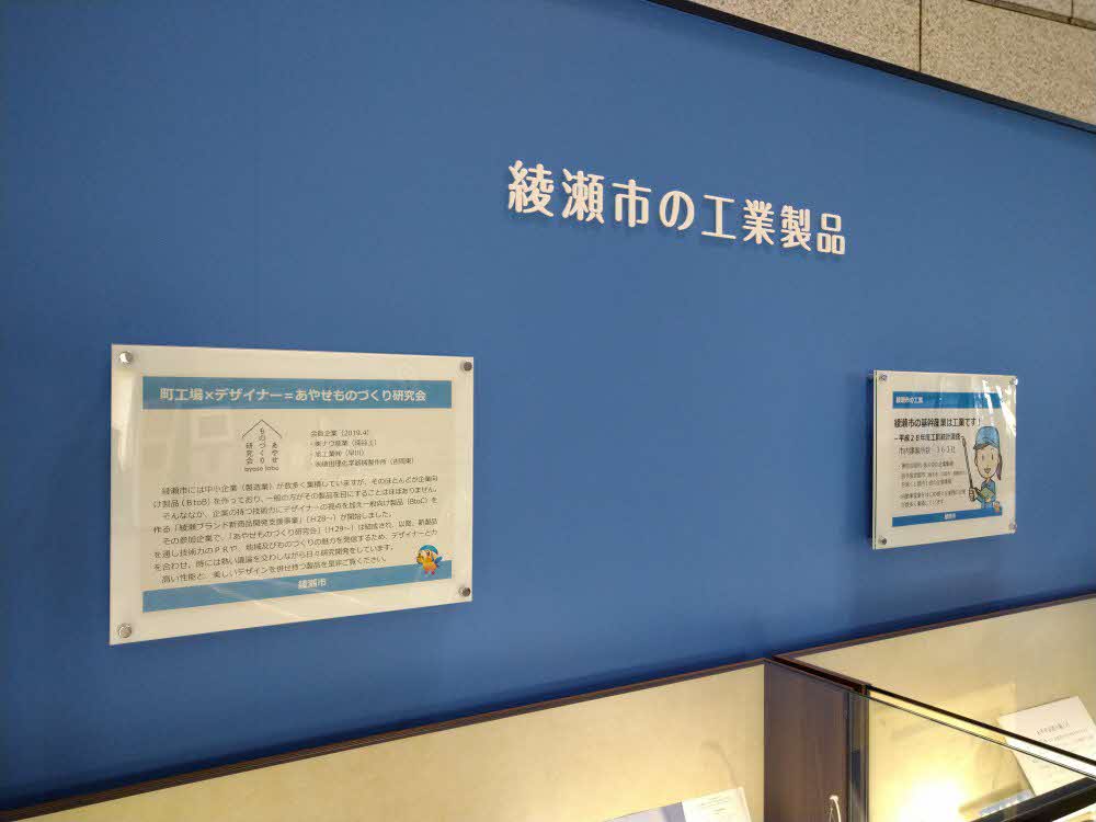 「綾瀬市の工業製品」と書かれた青い壁に掲示されている資料の写真