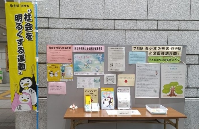 「社会を明るくする運動」と書かれたのぼり旗や掲示板にポスター、長机の上にパンフレットが置かれている紹介ブースの写真