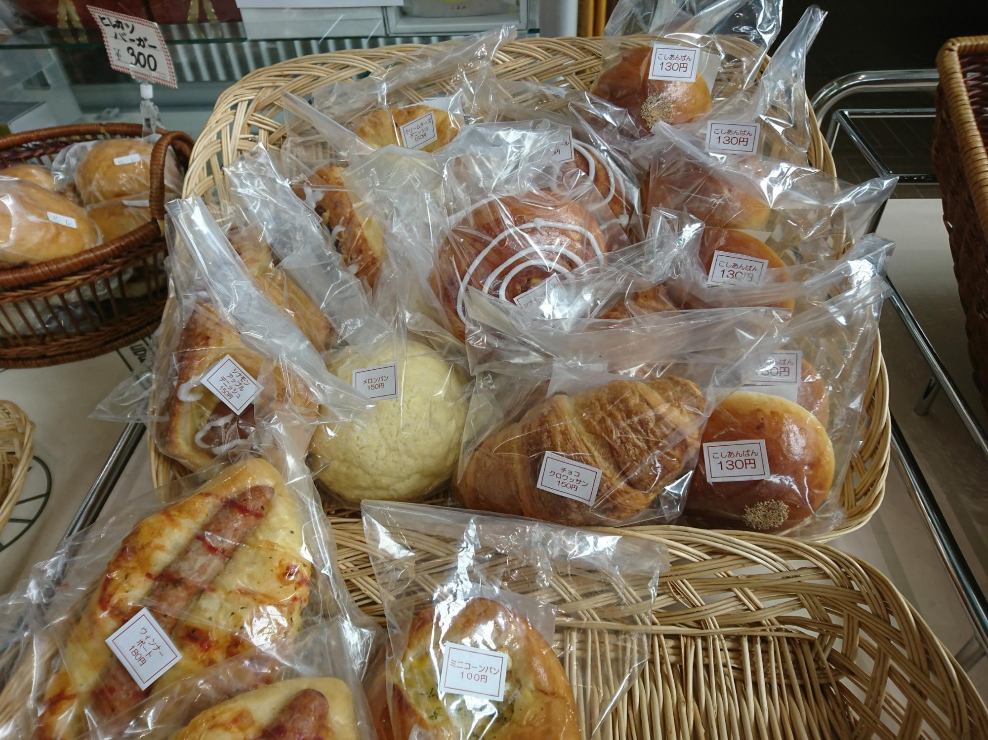 カゴの中に沢山の種類の透明の袋に入ったパンが1個ずつ置かれている写真