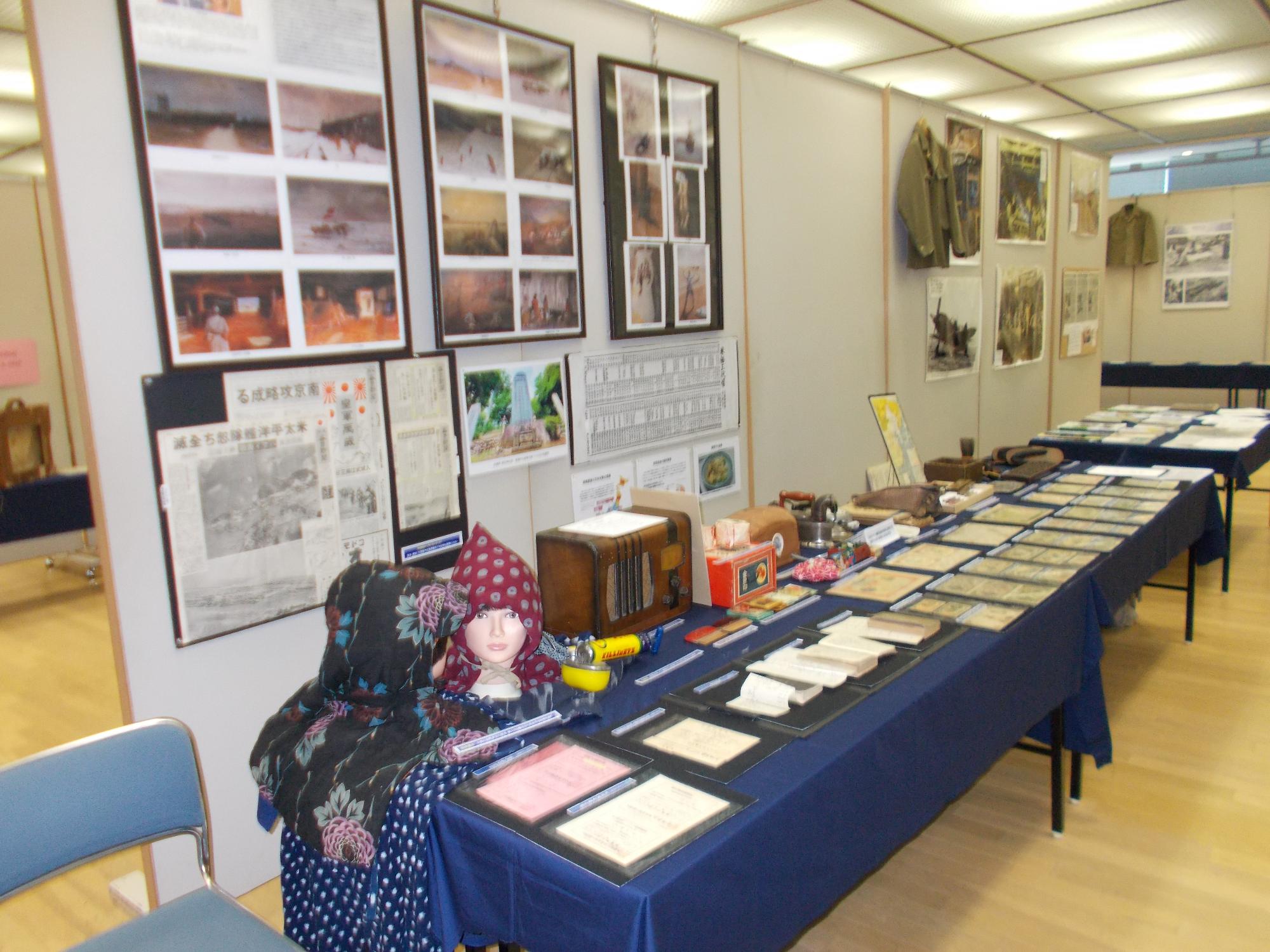 展示ホールで開催された平和展の展示品を見ている来場者たちの写真