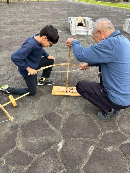 弓ぎり方を用いた火起こしの様子