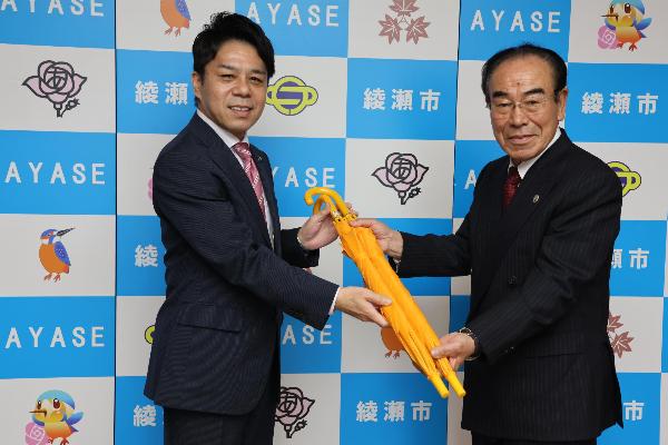 古郡会長から橘川市長へ子ども安全傘を寄贈している様子