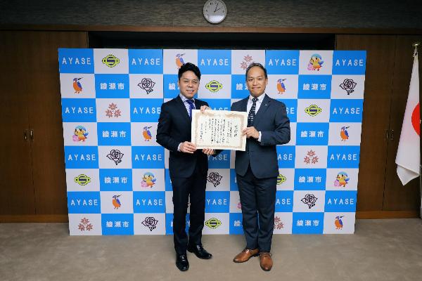 古郡会長から橘川市長へ子ども安全傘を寄贈している様子