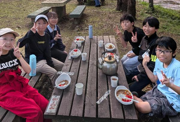 野外炊事で作ったカレーを食べる様子