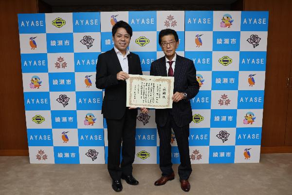 記念撮影の様子（左から橘川市長と田中耕二代表取締役社長）