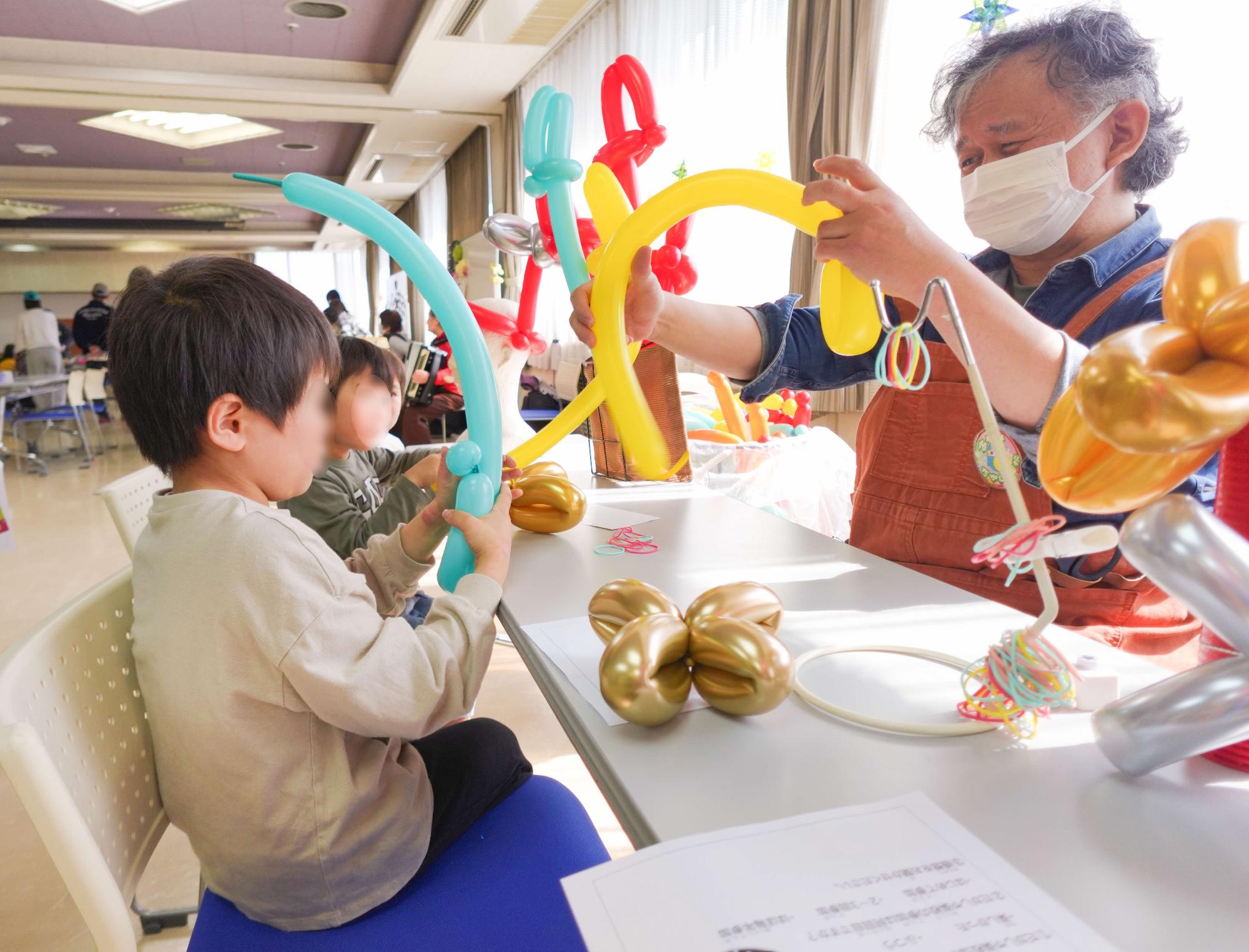 だがしや楽校で男性が子どもたちにバルーンアートを教える様子