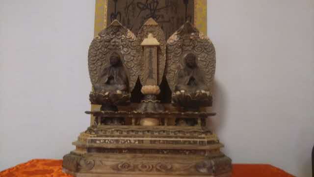 中央に掛け軸があり、左に釈迦如来坐像、右に多宝如来座像が座っている一塔両尊像の写真