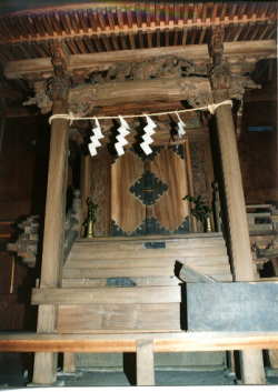 木造の宮造りで、しめ縄に市でが下げられた上部の柱に彫刻が施されている小園子之社本殿の写真