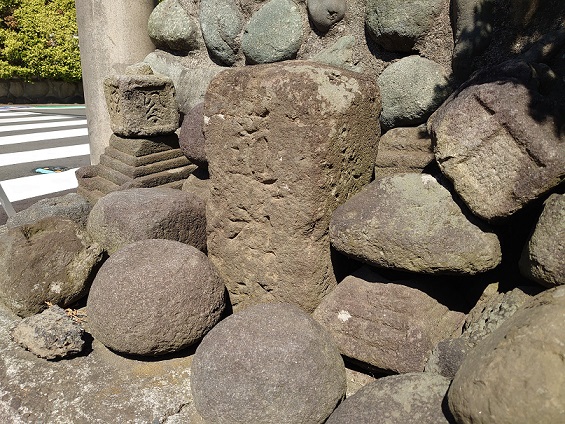 複数の大きな石が周りに置かれ、文字が刻まれ、長方形の形をした寺尾台の道祖神の写真