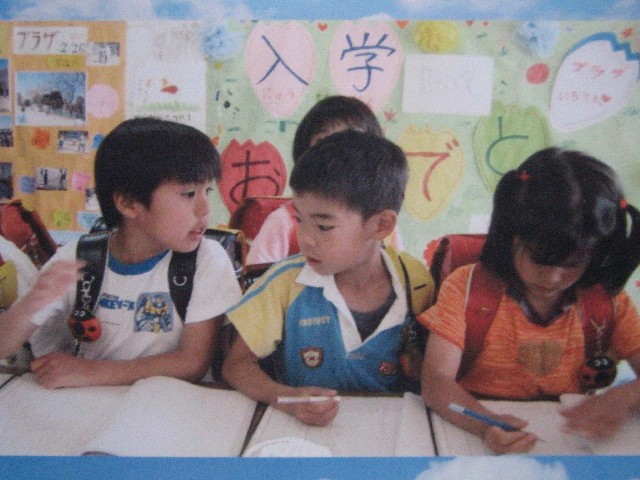 ランドセルを背負って並んで座り机にノートを広げている3人の子どもの写真