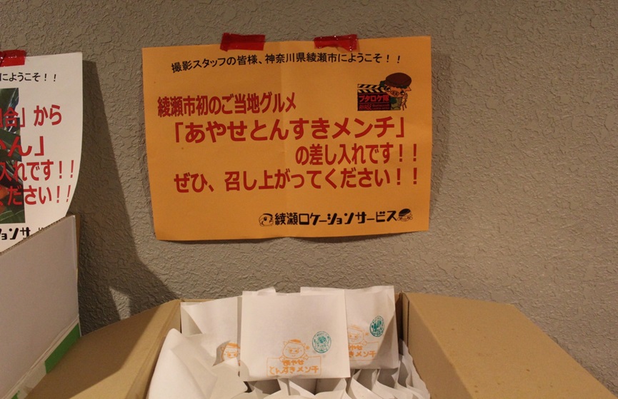 綾瀬市のご当地グルメ「あやせとんすきメンチ」の差し入れです。ぜひ、召し上がってください。と書かれた紙と段ボール箱いっぱいに入った、あやせとんすきメンチの写真
