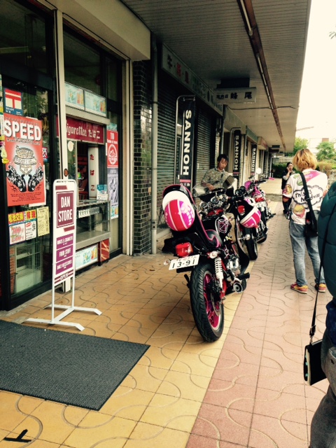 2台のバイクが縦に並べて停められており、周りにスタッフの方がいるお店の入口付近の写真