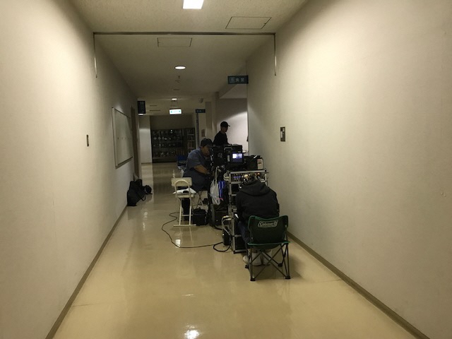 廊下に設置されたモニターを確認しているスタッフの方々の写真
