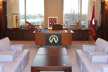中央に長方形のテーブルに白いソファーが2脚ずつ設置され、その奥の大きな窓の前に市長席がある市長の部屋の写真