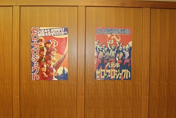 壁に「ゼロ・プロジェクト」と書かれた2種類のポスターが飾られている写真