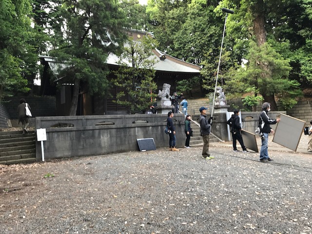 お寺の境内で、スタッフの方々が大きな板のレフ板や長い棒のついた「ガンマイク」を持ったスタッフの方々が撮影を行っている様子の写真