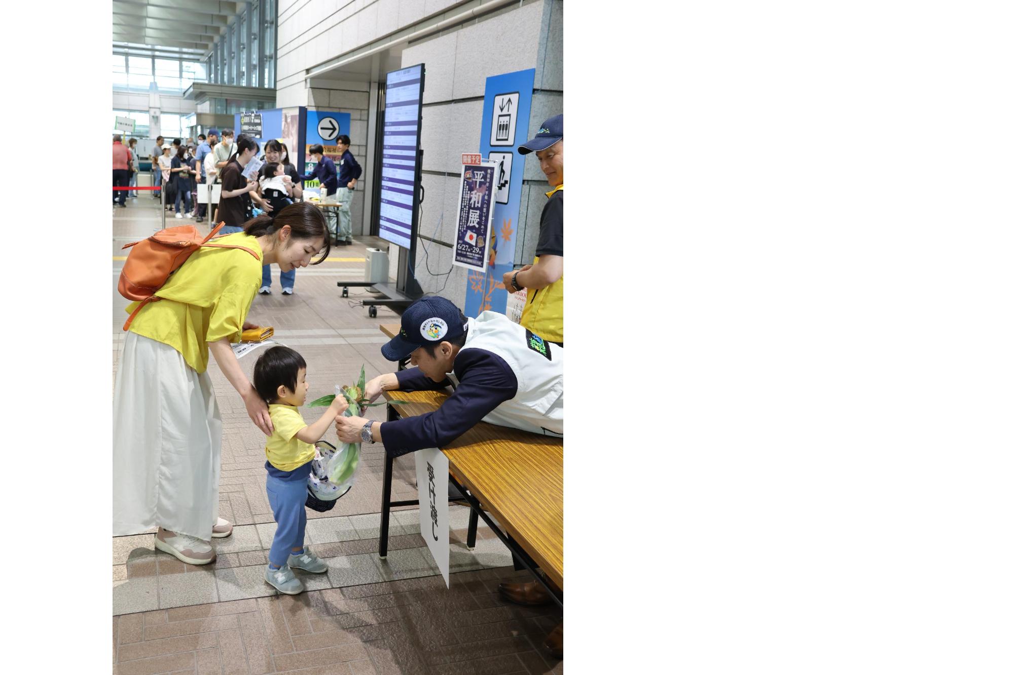 販売会で市長が子供にトウモロコシを渡している画像