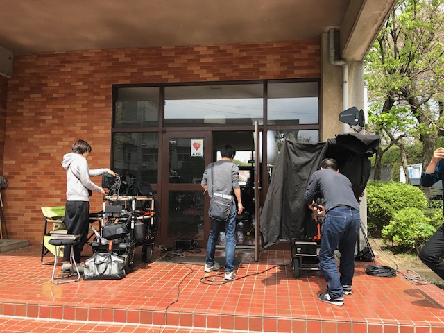 玄関前に撮影機材が置かれ、スタッフの方々が作業をしている様子を写した写真