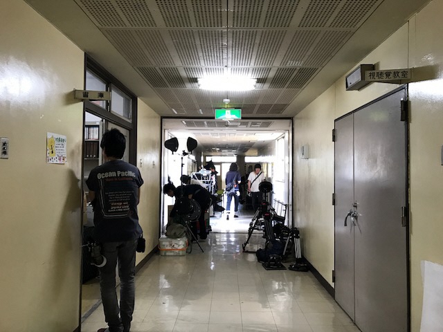 廊下に沢山の撮影機材が置かれ、スタッフの方々が作業をしている撮影現場の写真