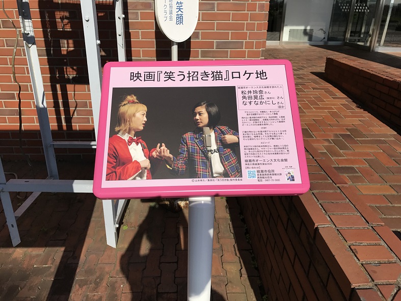 実際に綾瀬市オーエンス文化会館で撮影された松井玲奈さんと清水富美加さんが漫才をしているシーンの写真や撮影中のエピソードなどがかかれているロケ地看板の写真