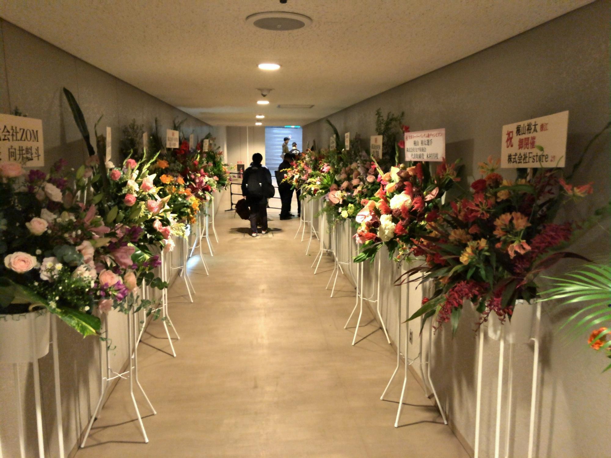 左右に様々な花で生けられたスタンド花が間隔をあけて並んでいる写真