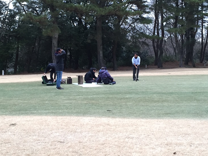 ゴルフ場で男性がクラブを持ち、ゴルフをしている様子を撮影している撮影現場の写真