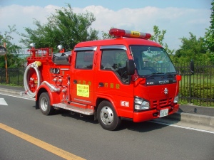 道路路肩に停まっている赤い普通消防ポンプ自動車の写真