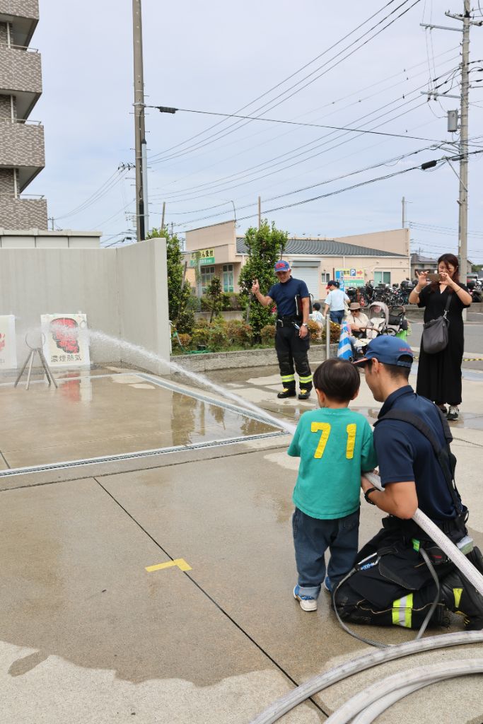 子どもが消防用ホースで放水する様子