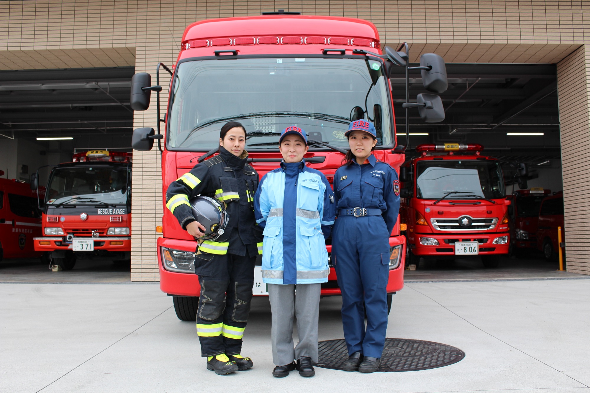 制服を着て消防自動車の前に立っている3名の女性消防吏員の写真