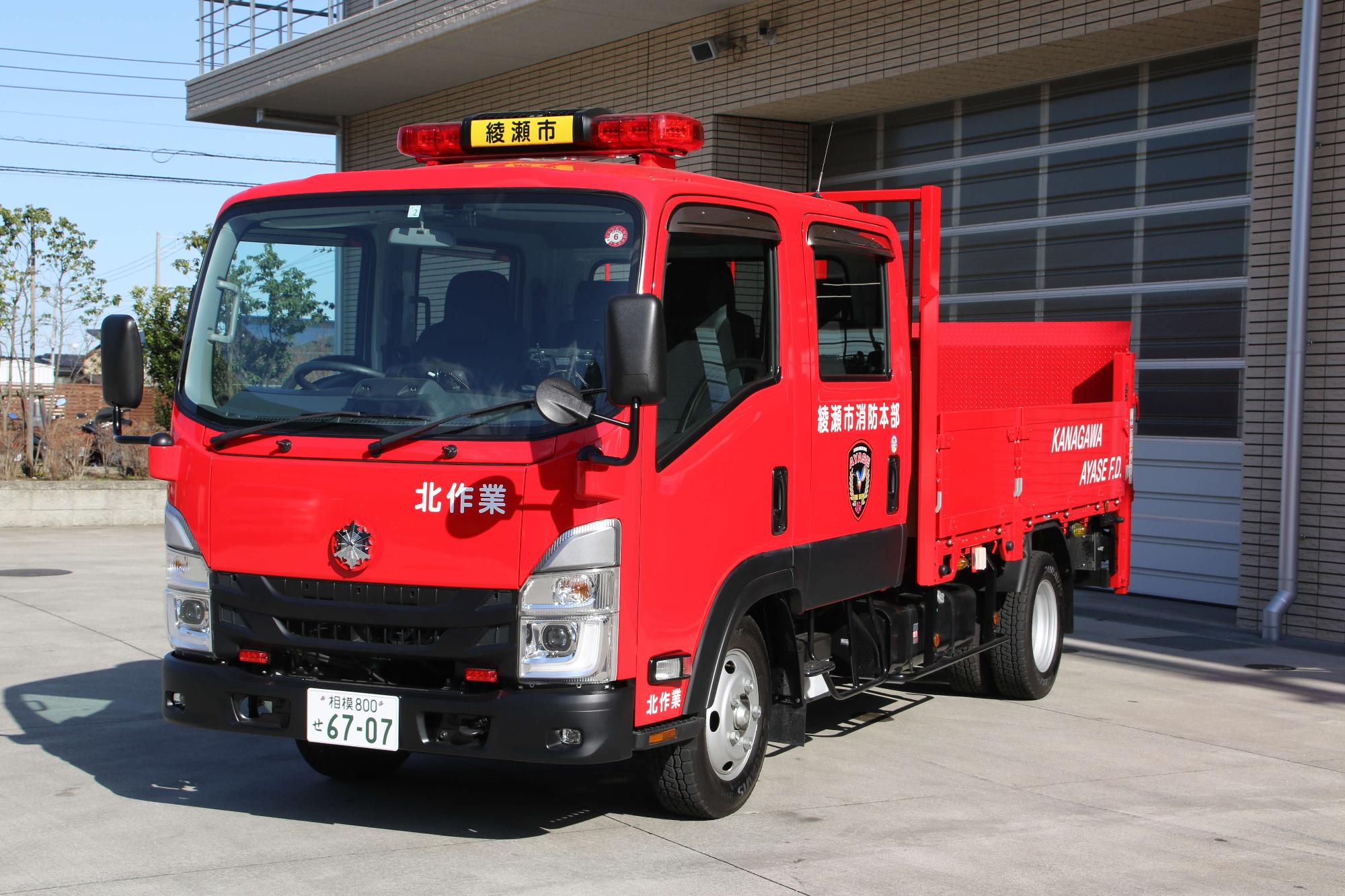 赤色の車体で、荷台に屋根のない平ボディ型トラックの写真