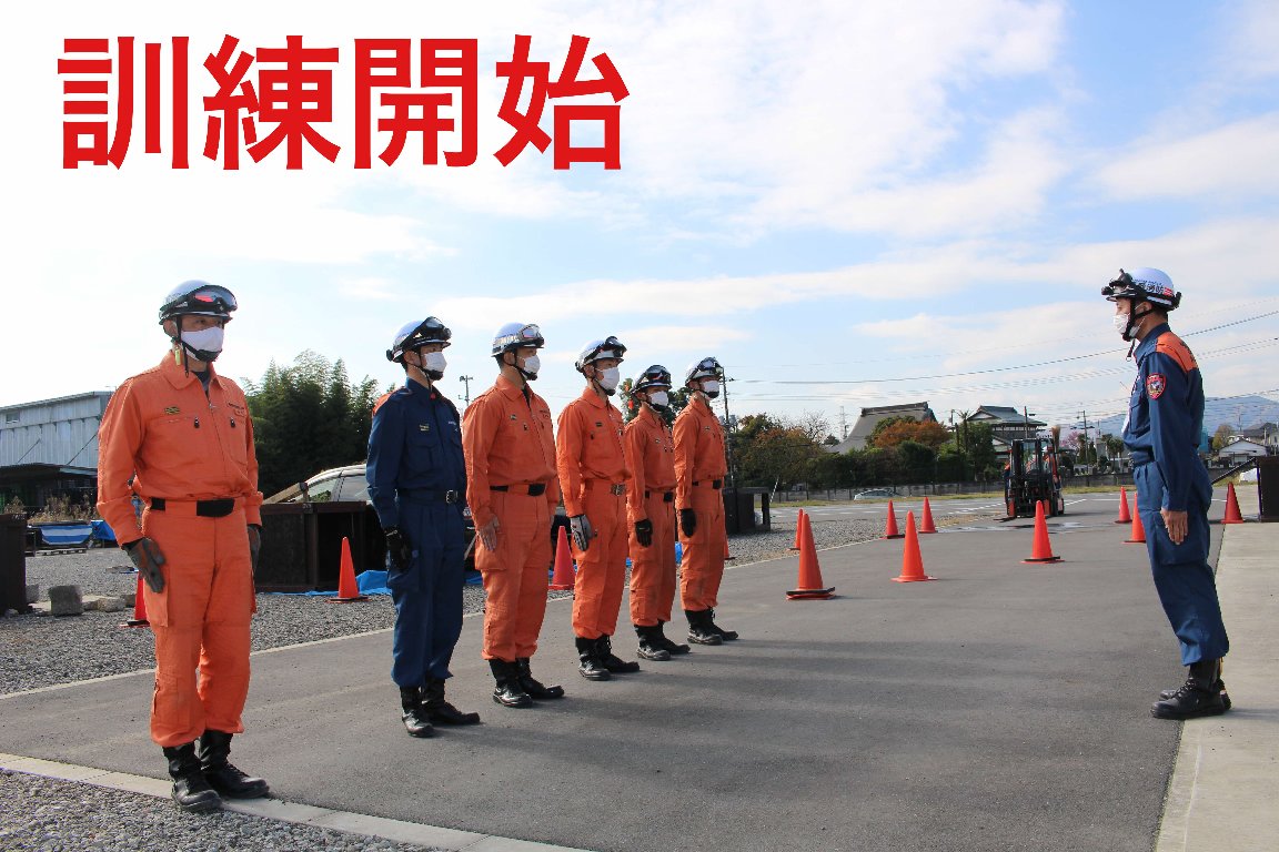 オレンジ色の活動服を着た消防の方々が横一列に整列し、前に立つ青色の活動服を着た方の前に並んでいる写真