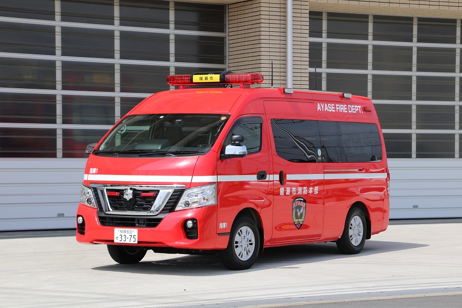 赤い車体の中央に車体を1周囲むように白い線が引かれ、車体横に綾瀬市消防本部のエンブレムがプリントされている指揮車の写真