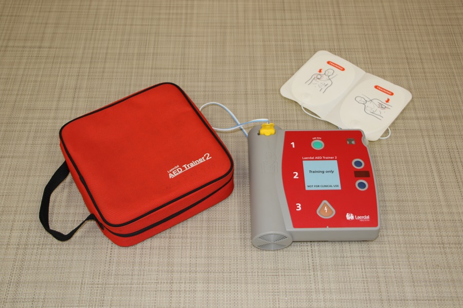 ボタンを押して電源を入れるタイプのAED機器と赤色のケースの写真