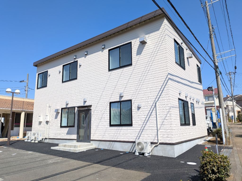緑のフェンスの中にプランターが並び、2階建ての階段が建物横に設置され、2ケ所の入り口が建物の両脇にあるルピナス教室の全景を写した写真